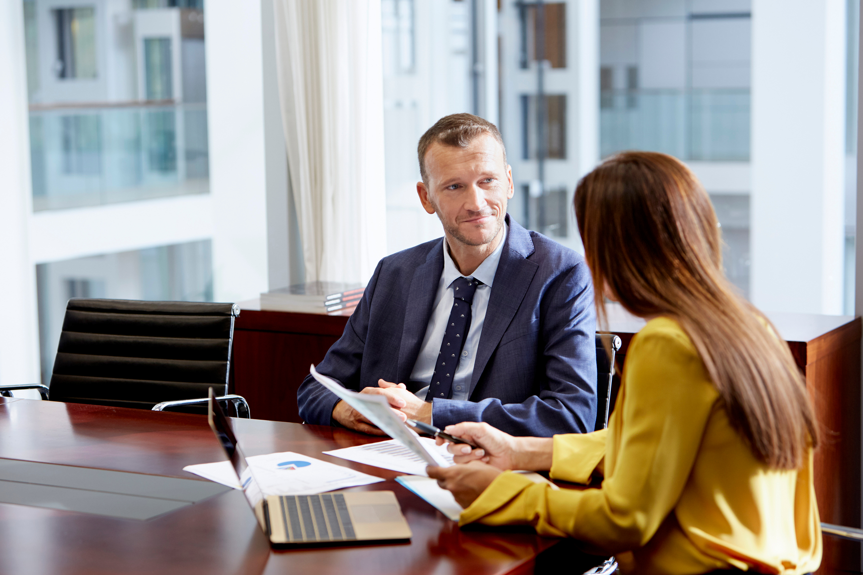 Man and woman sitt around a table talking in an office