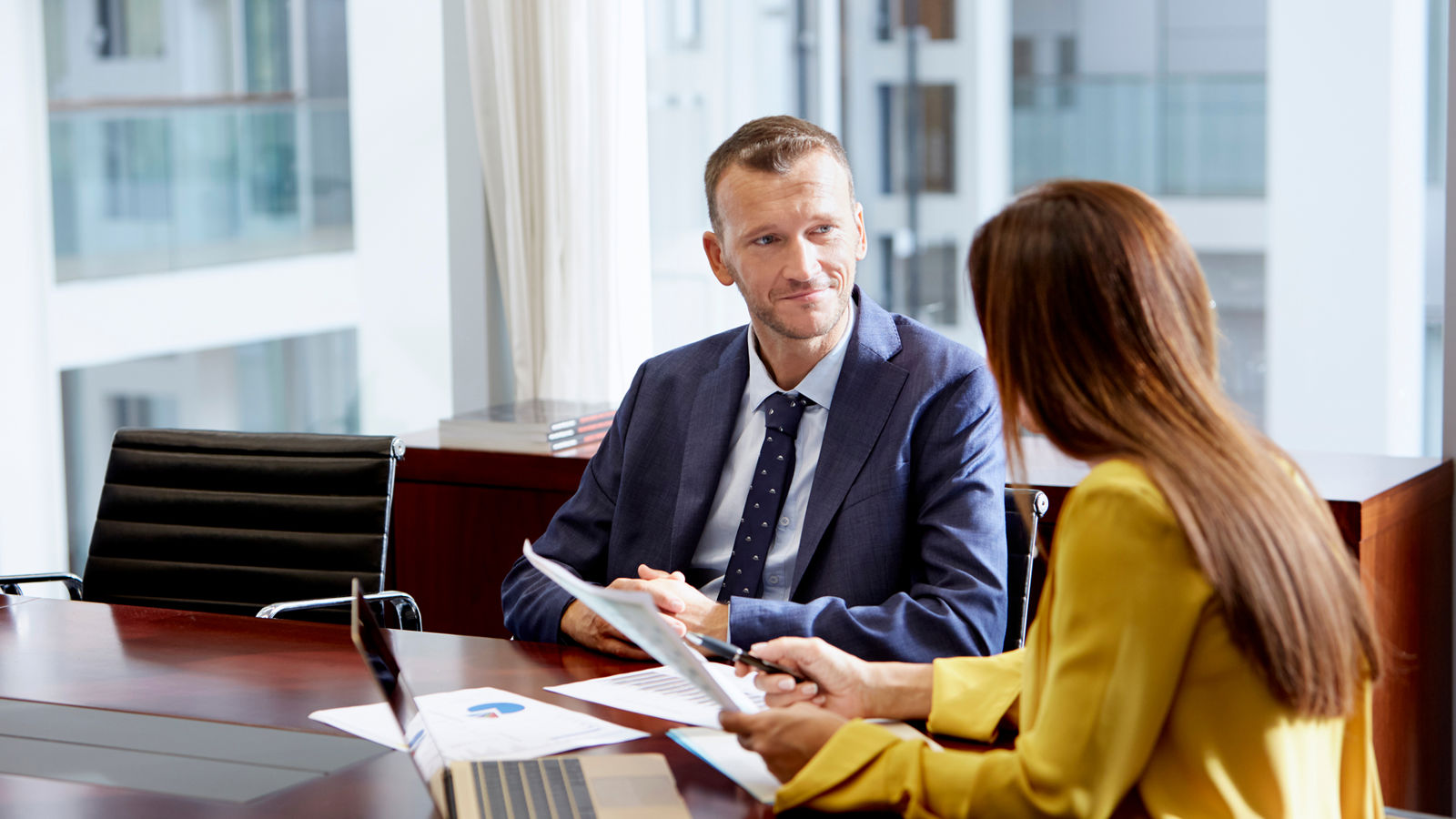 Man and woman sitting around a table talking in an office